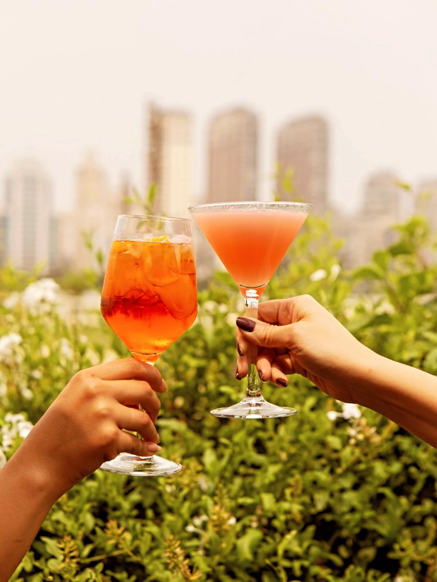 A toast with cocktails and the São Paulo skyline behind